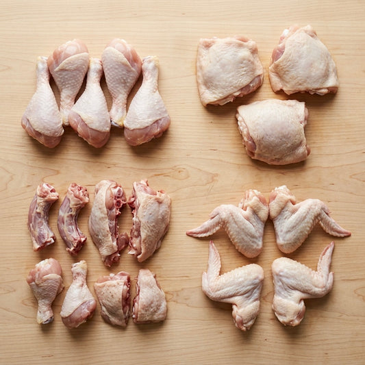 Raw chicken parts including legs, thighs, and wings on a wooden surface.